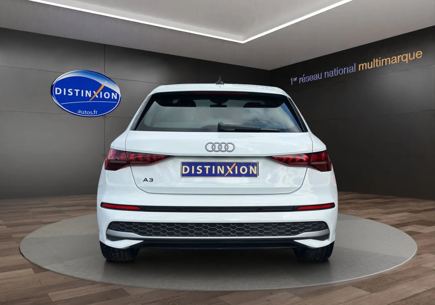 Vue arrière d'une Audi A3 Sportback blanche Arkona 2024 avec feux LED et logo Distinxion visible.