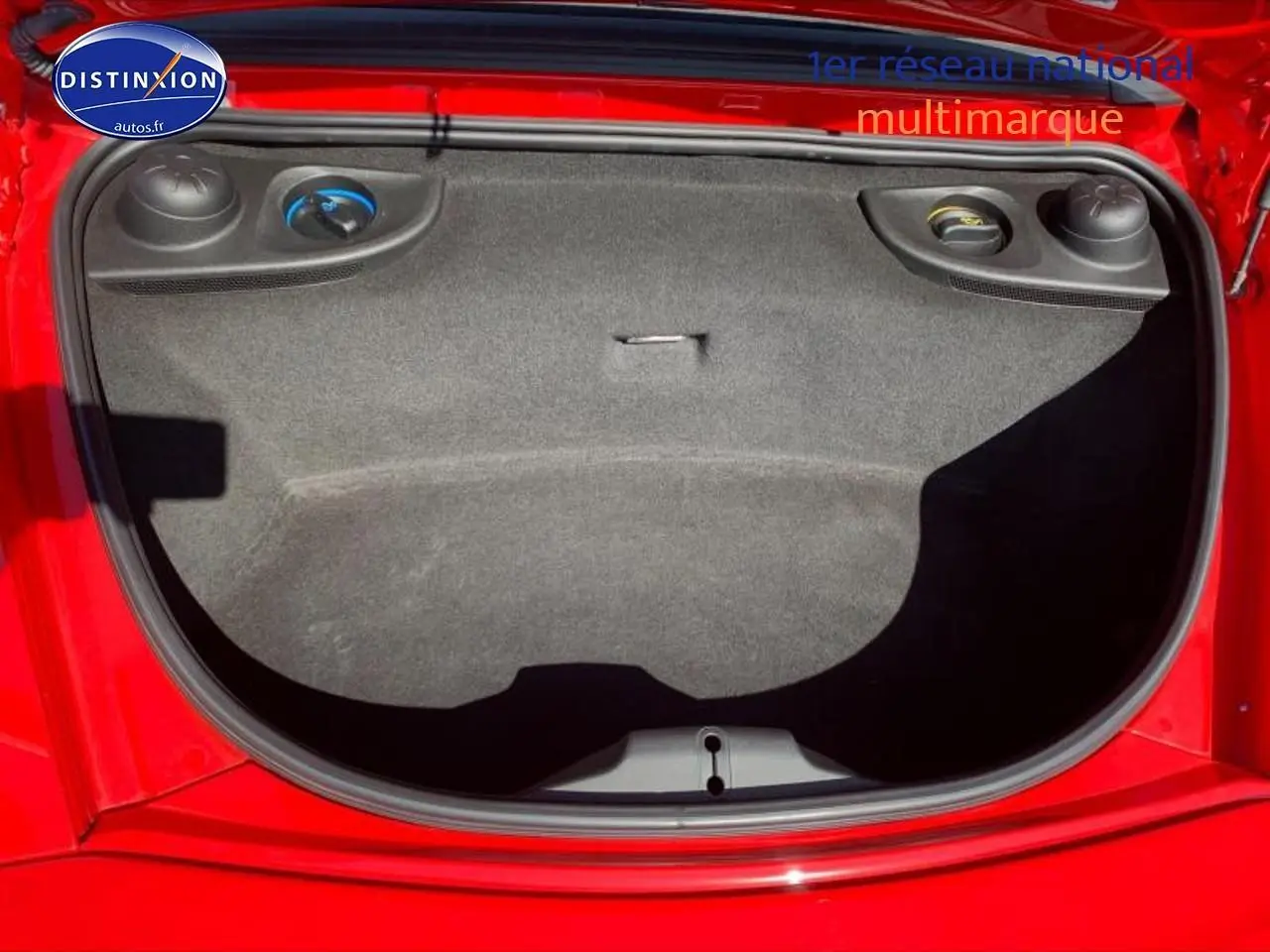 Vue plongeante sur le coffre avant rouge d'une Porsche Boxster 981, montrant son espace de rangement vide.