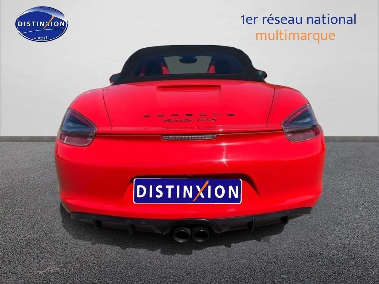 Vue arrière d'une Porsche Boxster GTS rouge avec capote noire et double sortie d'échappement centrale.