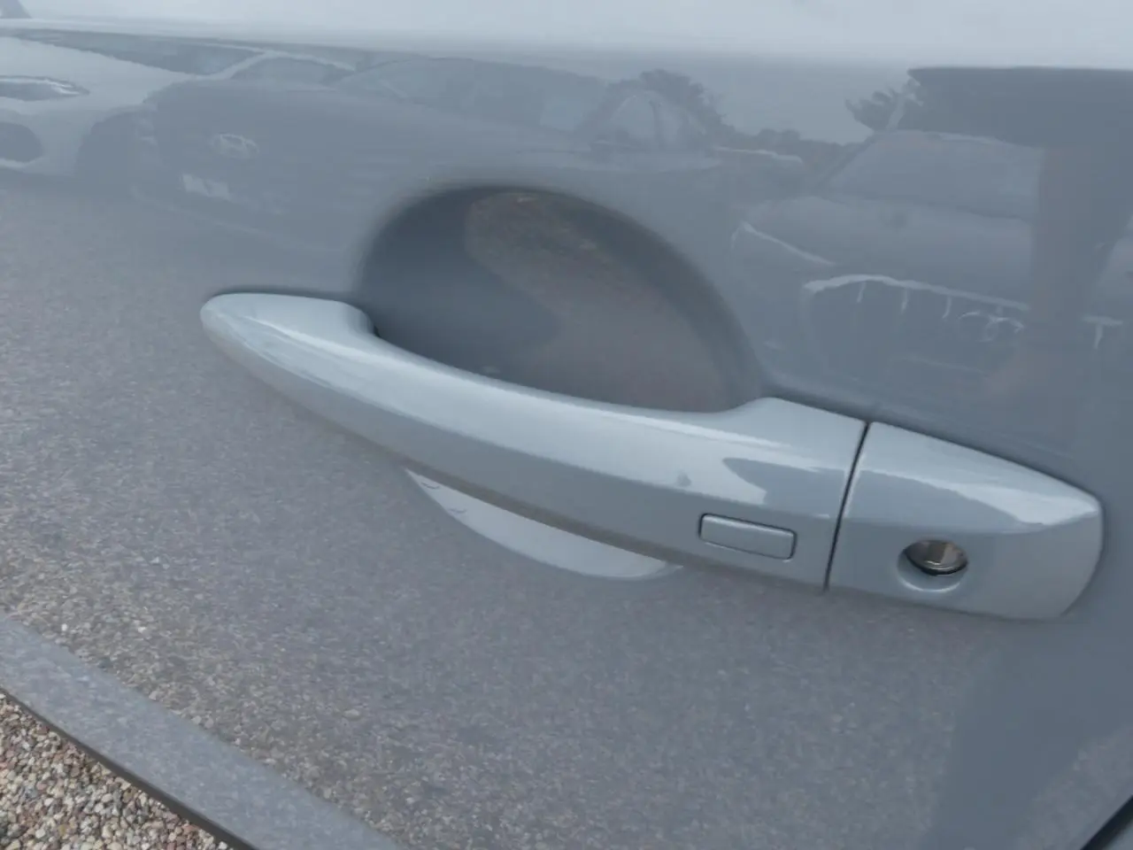 Poignée de porte côté gauche gris métallisé du Nissan Qashqai 1.5 e-Power avec bouton de déverrouillage.