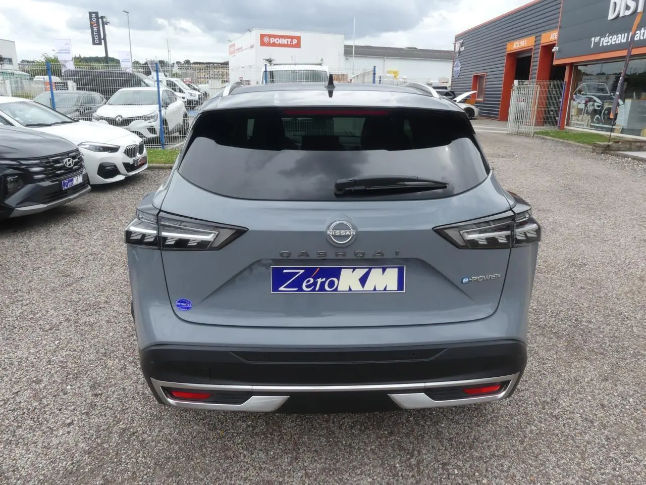 Vue arrière d'un Nissan Qashqai gris métallisé avec badges e-Power et plaque Zero KM visible.