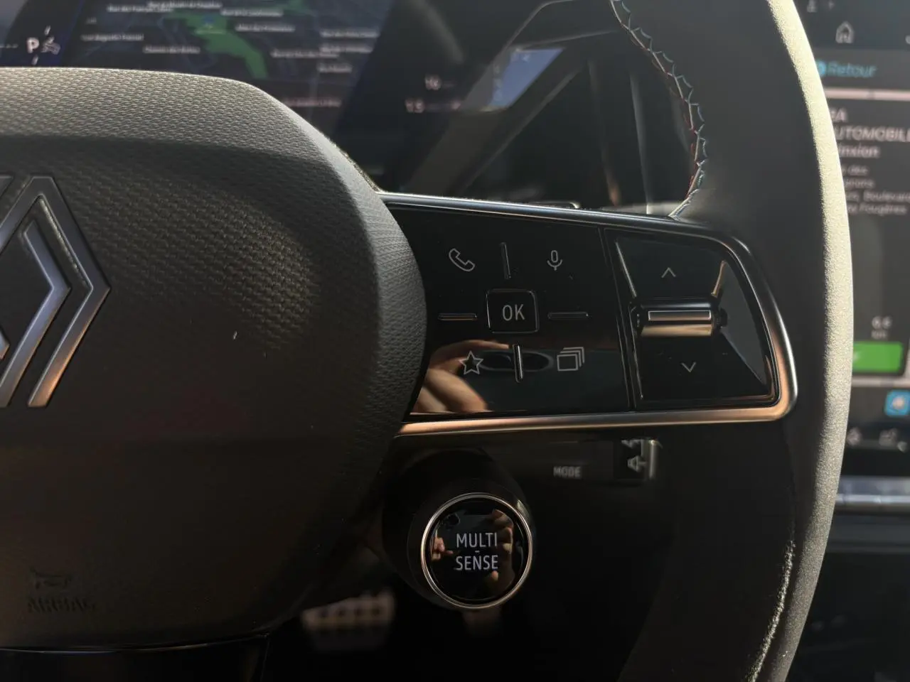 Gros plan sur le volant Alcantara du Renault Rafale E-Tech avec commandes multifonctions et bouton Multi-Sense.