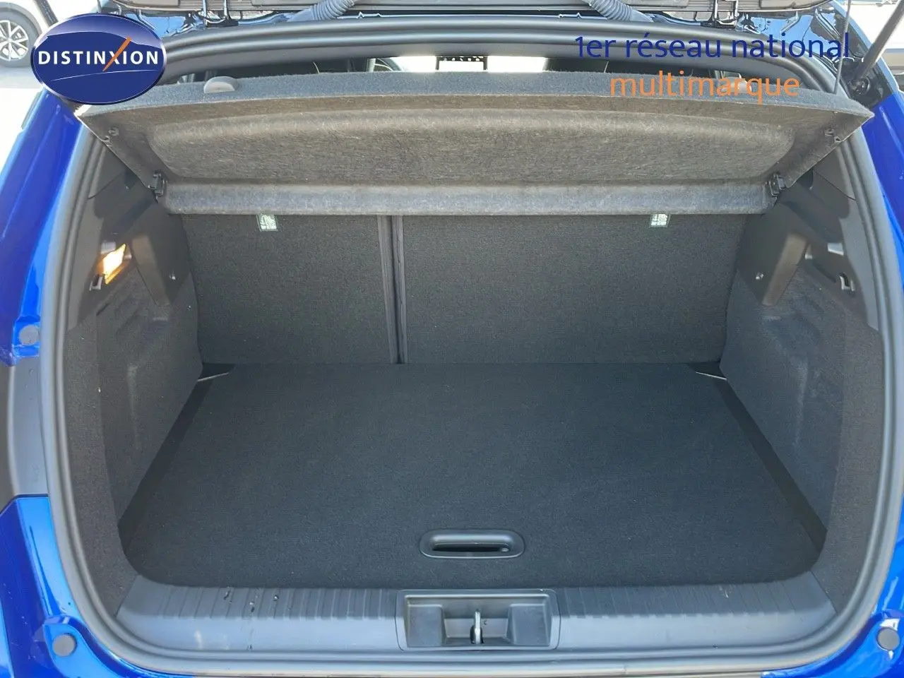 Coffre ouvert vu de l'arrière d'un Renault Captur bleu iron metal avec toit noir, montrant l'espace de chargement vide.