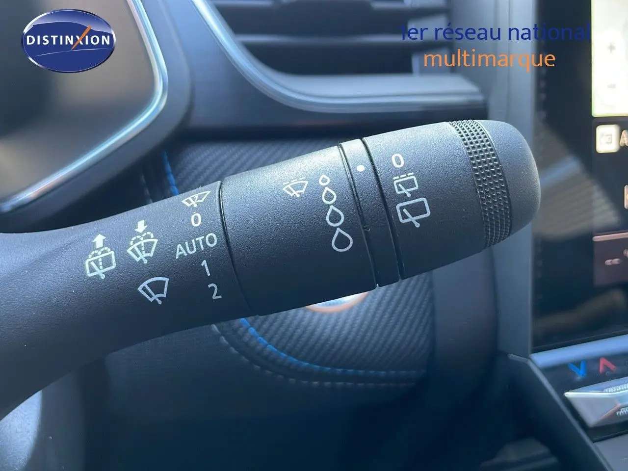 Gros plan sur la commande d'essuie-glace du Renault Captur E-Tech hybride 2025, intérieur noir avec surpiqûres bleues.