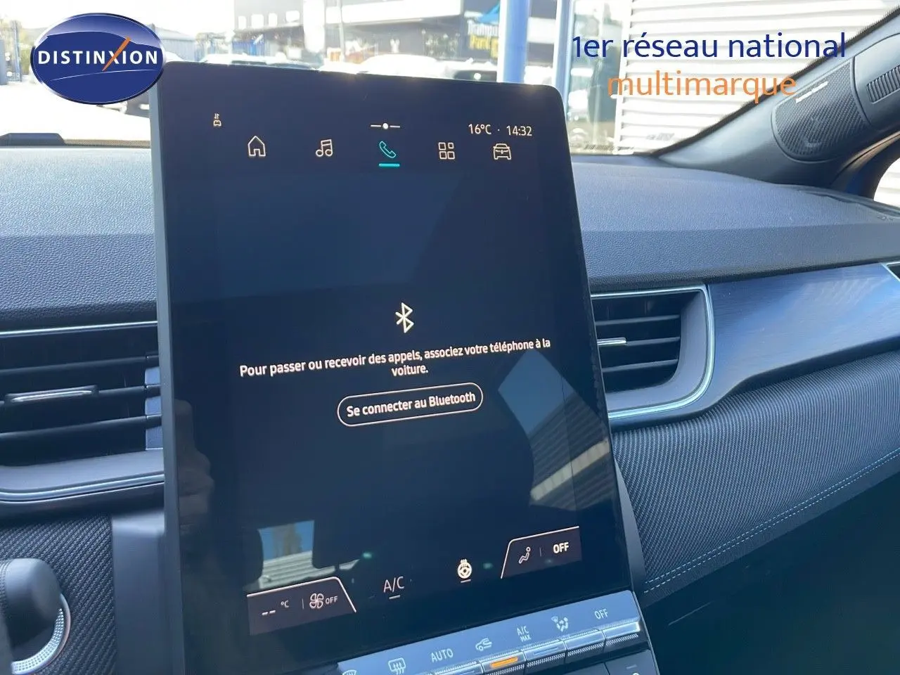 Écran tactile central allumé dans l’habitacle du Renault Captur bleu iron metal avec toit noir, vue côté droit.