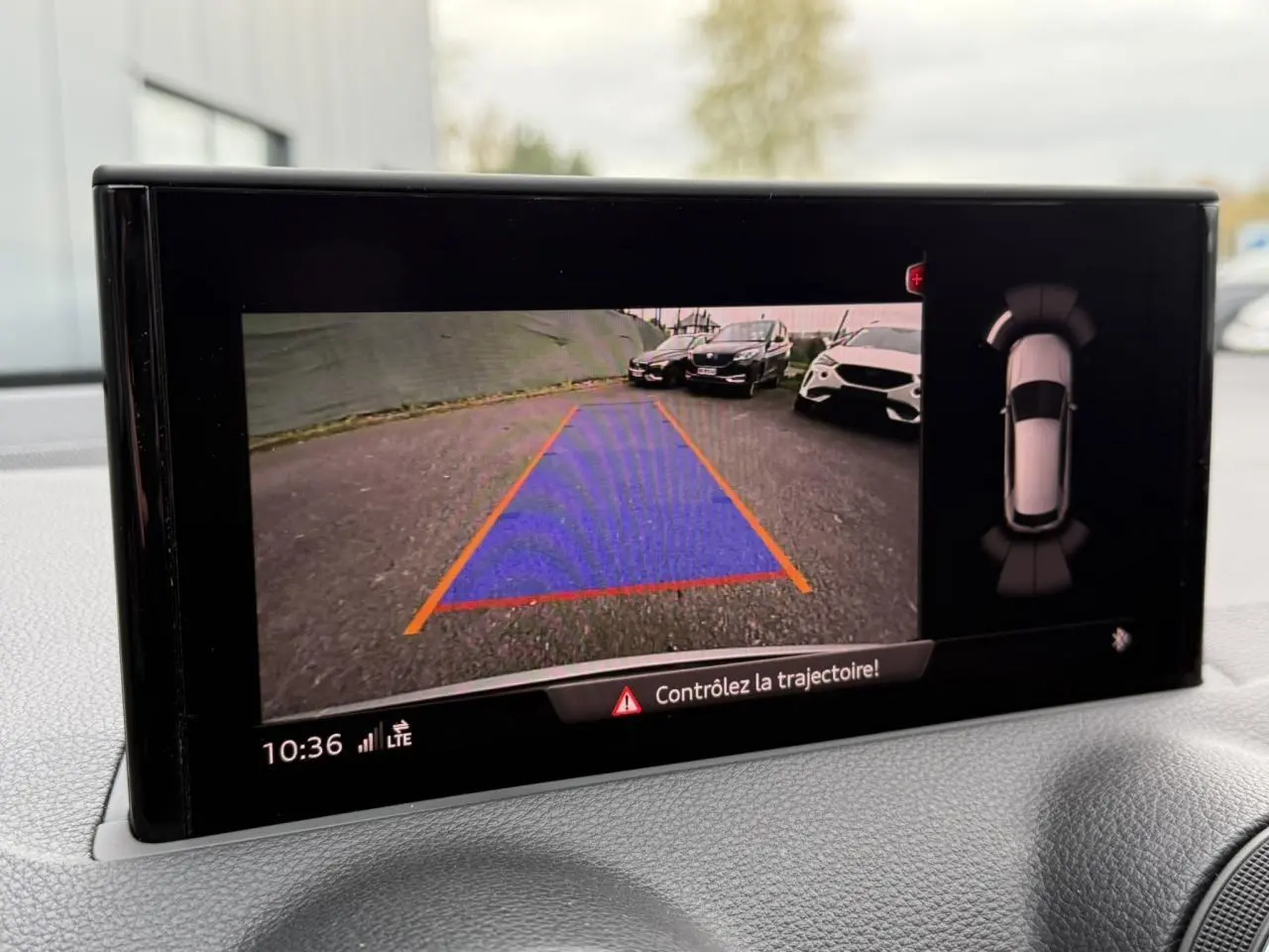 Affichage caméra de recul et aide au stationnement sur Audi Q2 noir Mythe, vue intérieure du tableau de bord.