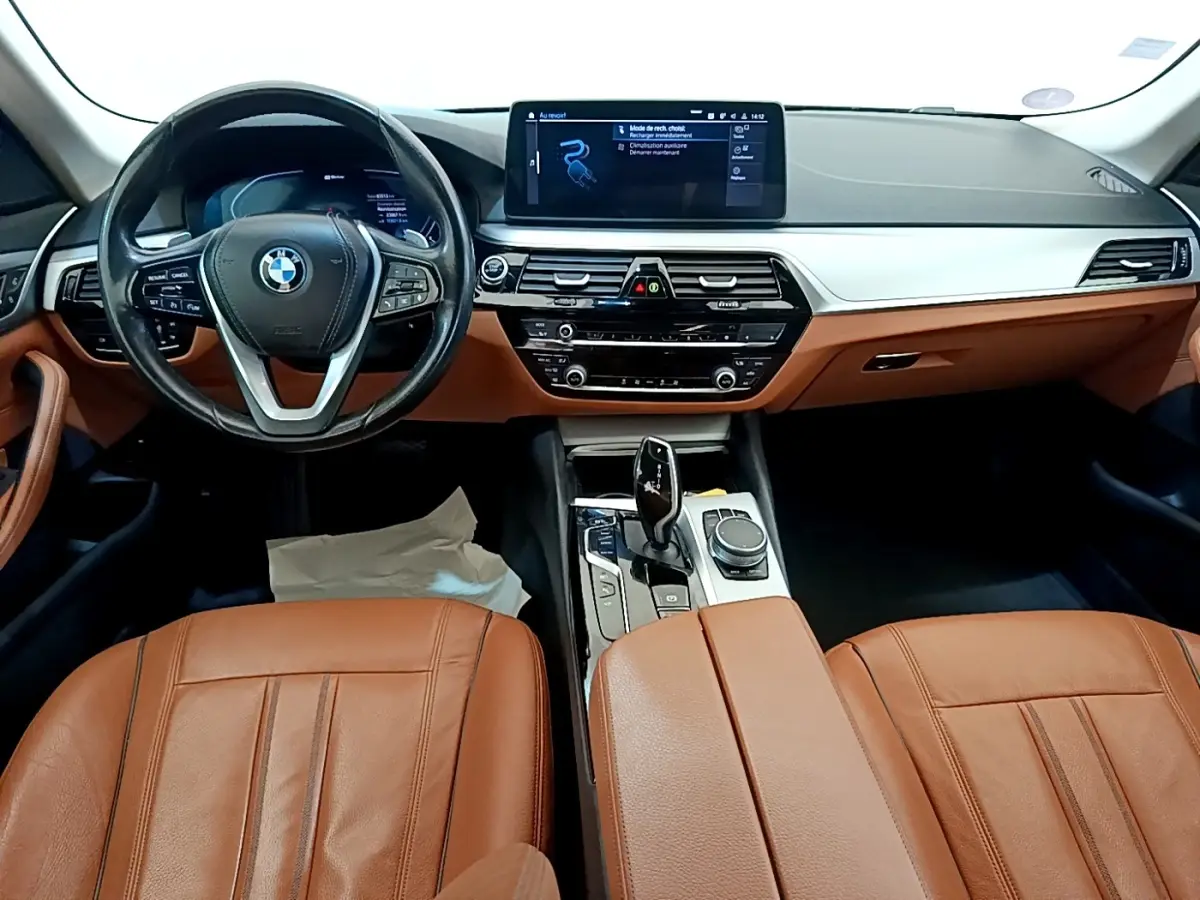 Vue intérieure avant de la BMW Série 5 Touring 530e 2022 avec sièges cuir marron et tableau de bord moderne noir et argent.