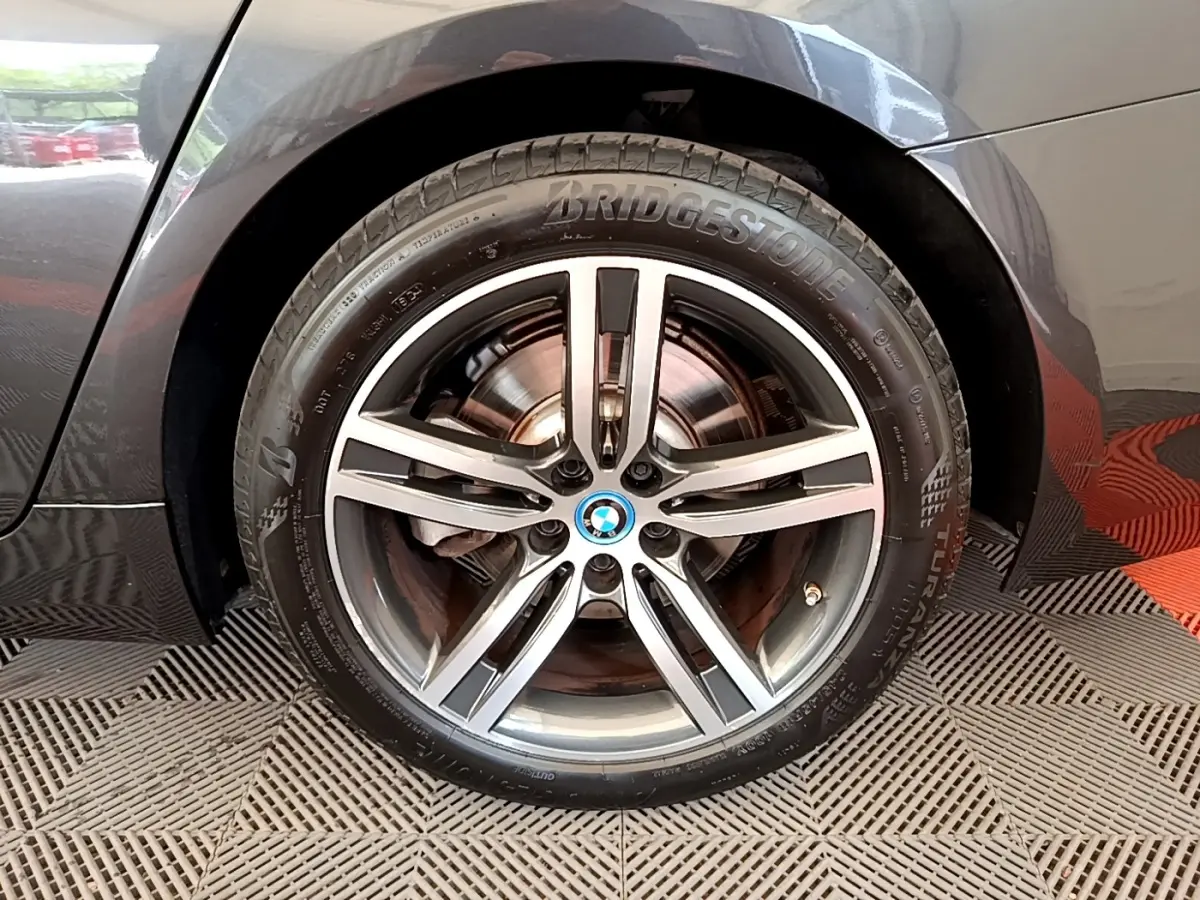 Gros plan sur la roue avant droite gris clair d’une BMW Série 5 Touring 530e avec jante alliage cinq branches.