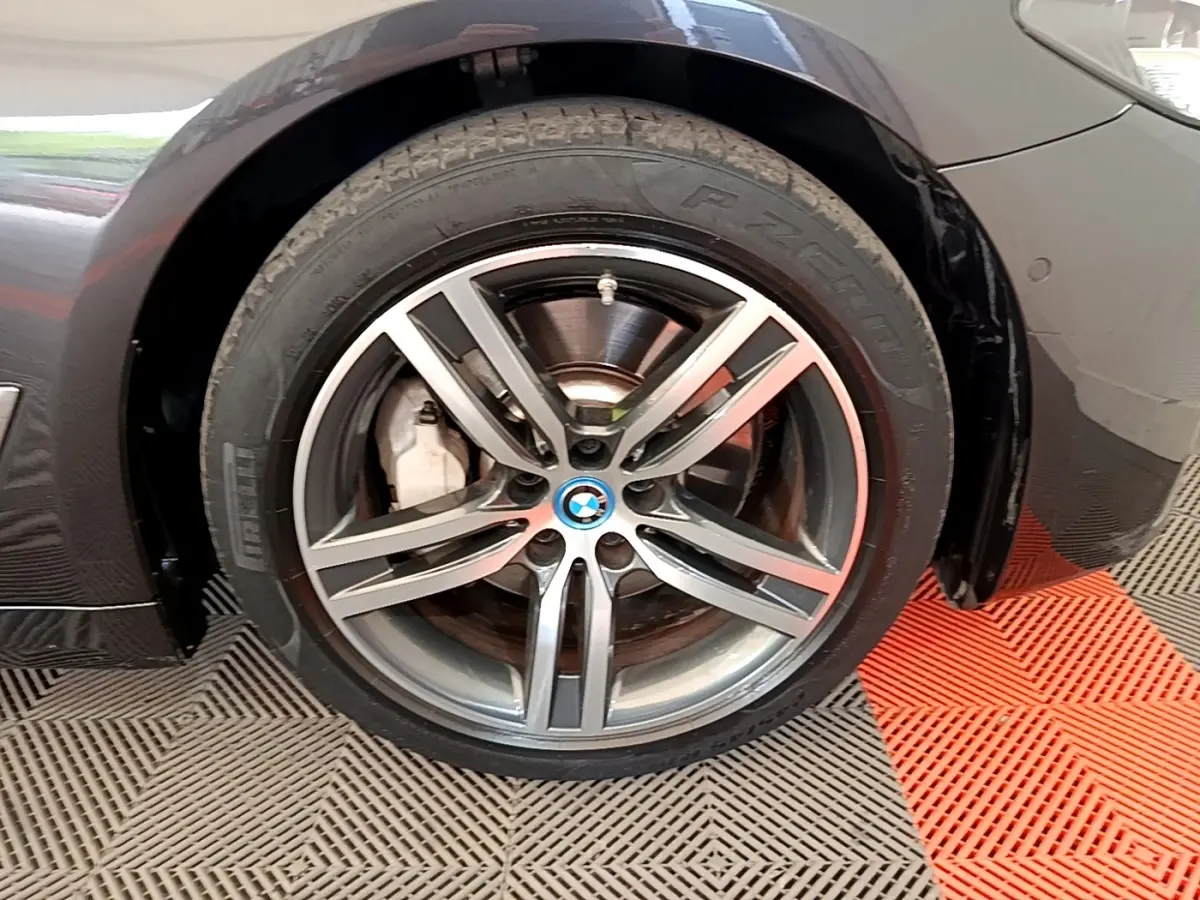 Gros plan sur la roue avant droite gris clair d’une BMW Série 5 Touring 530e avec jante alliage à cinq branches doubles.
