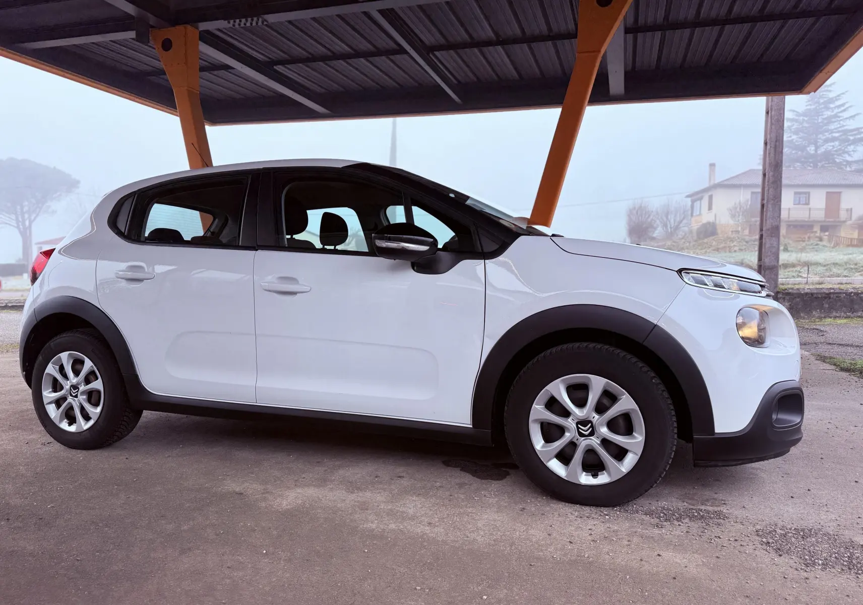 Vue latérale droite d'une Citroën C3 Société blanche de 2019, avec jantes alliage et protections noires sur les passages de roues.