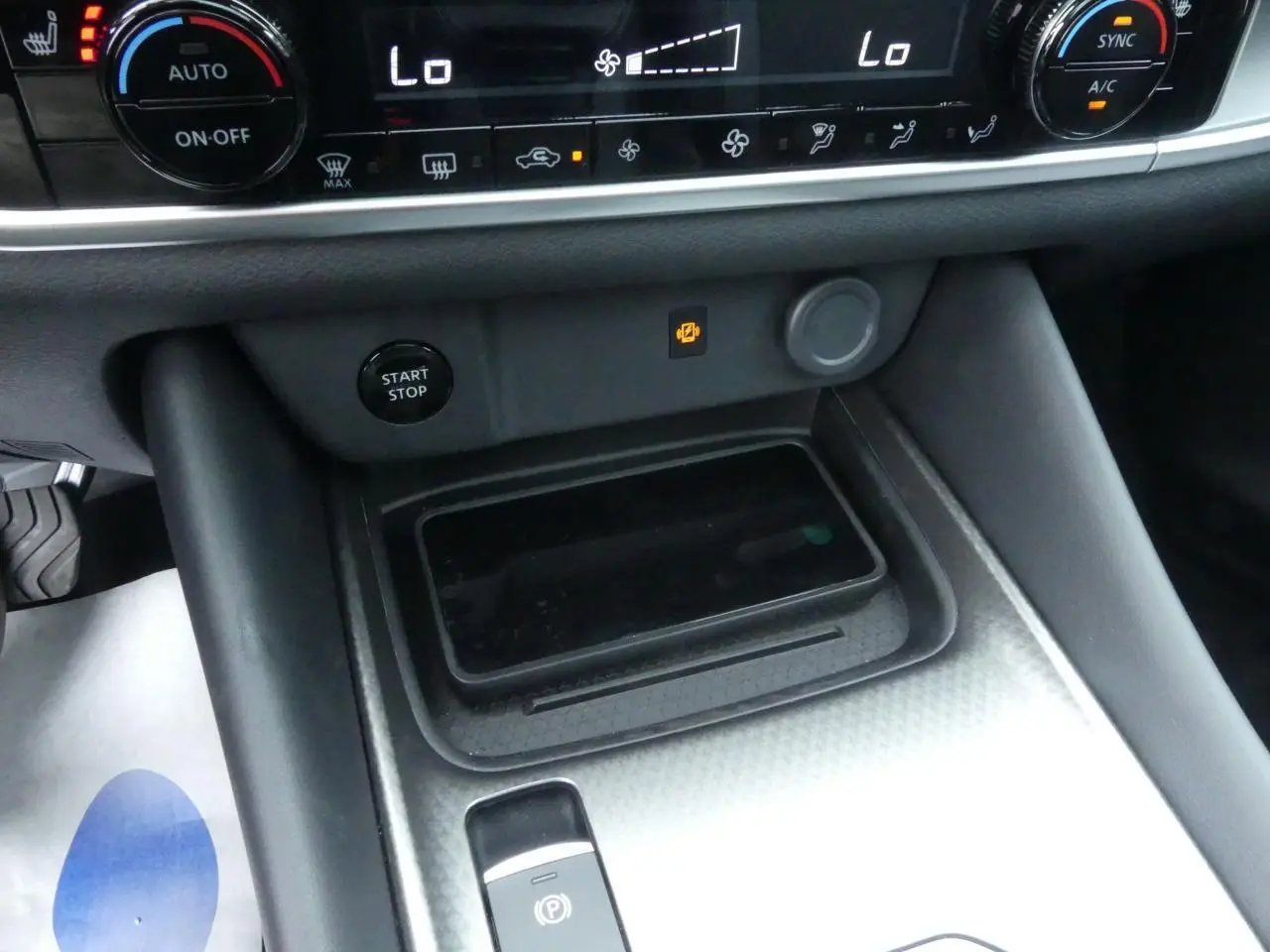 Vue rapprochée de la console centrale du Nissan Qashqai 2025 gris métallisé avec chargeur à induction et bouton Start/Stop.