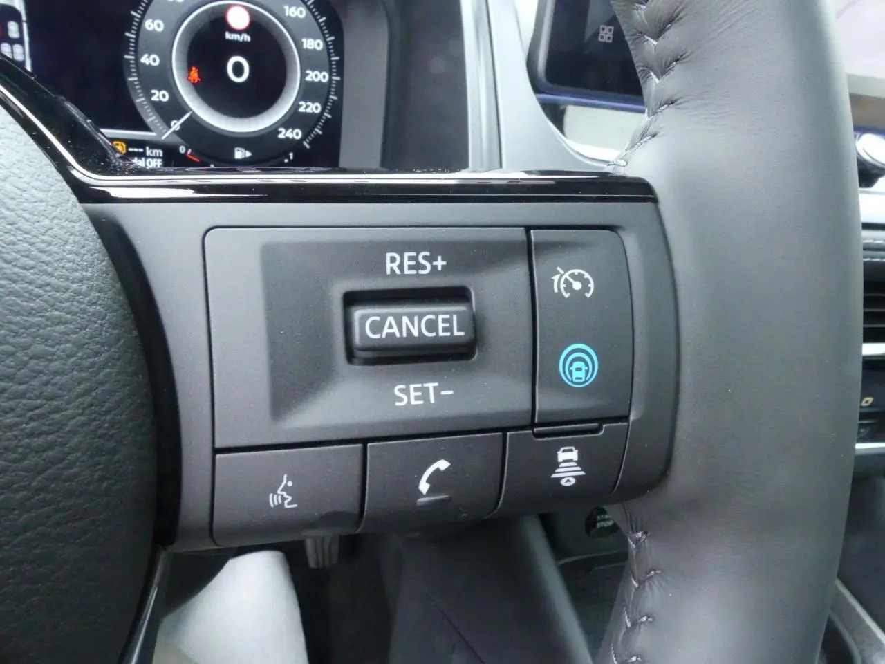 Gros plan sur les commandes du volant cuir noir du Nissan Qashqai gris métallisé, affichage numérique en arrière-plan.