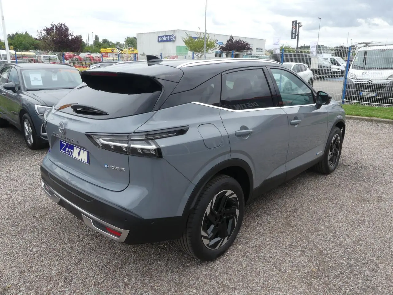 Vue 3/4 arrière droite du Nissan Qashqai gris métallisé avec toit noir et jantes alliage au design moderne.