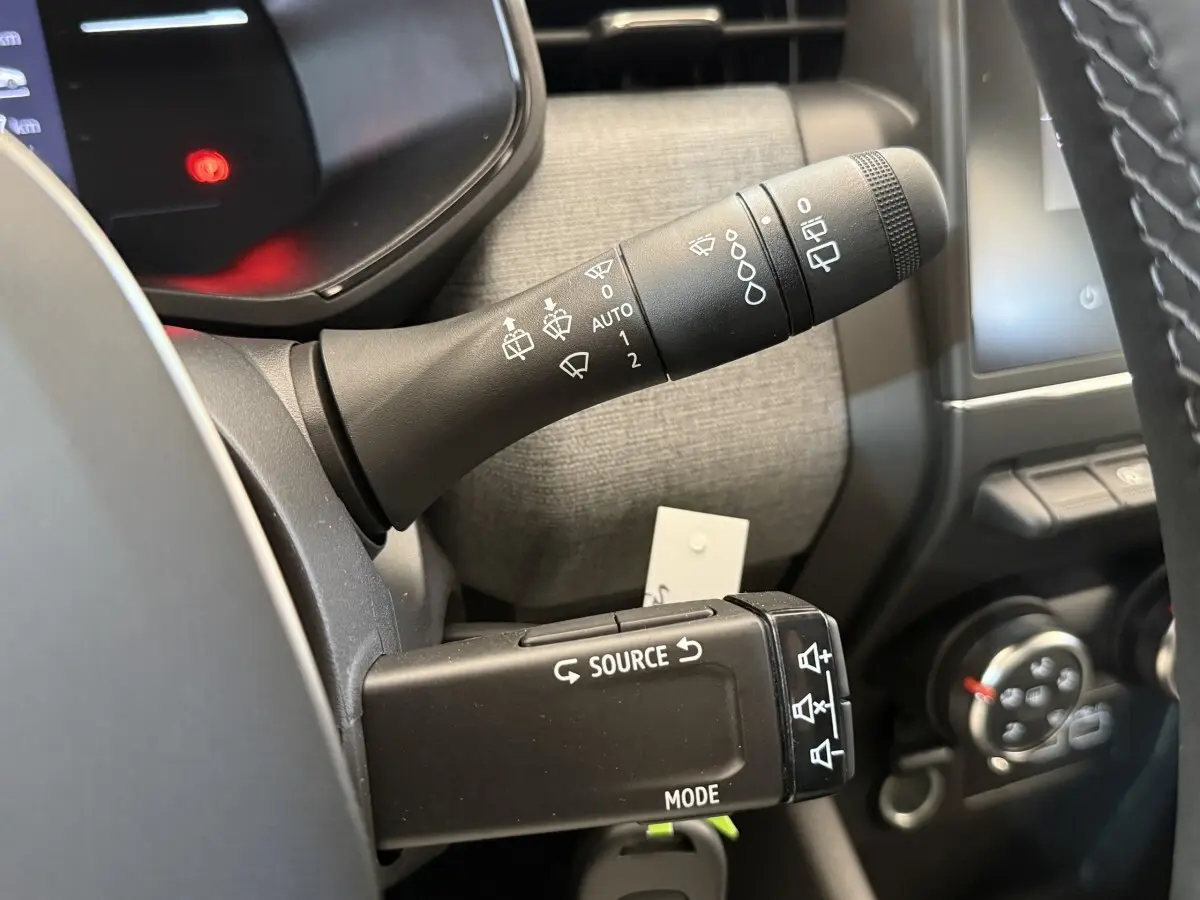 Gros plan sur les commandes au volant de la Renault Clio 2025, avec levier d'essuie-glace et boutons multimédia visibles.