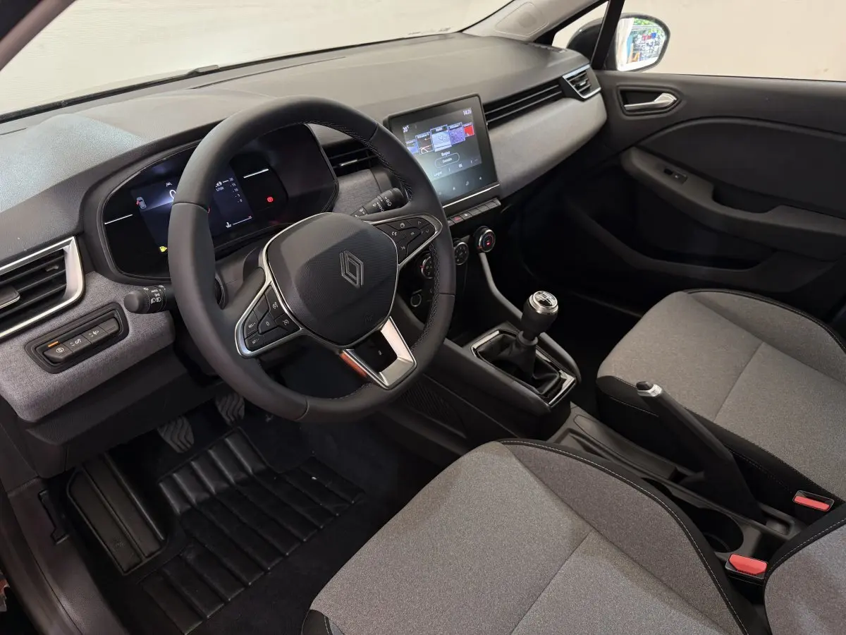 Intérieur de la Renault Clio Evolution Blue dCi 100 2025, vue côté conducteur, volant cuir et écran tactile central visible.