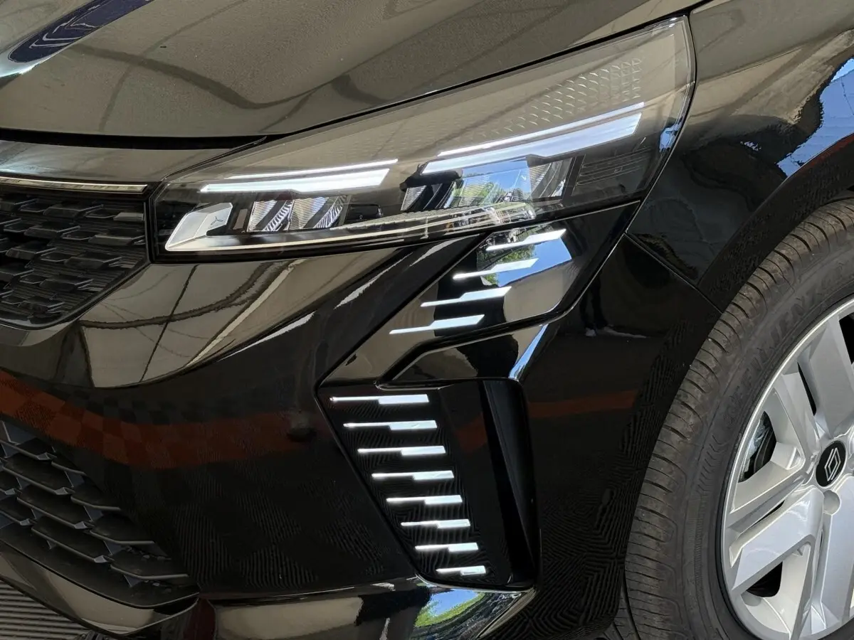 Gros plan sur le phare avant droit et la roue d’une Renault Clio noire 2025 avec feux LED distinctifs.