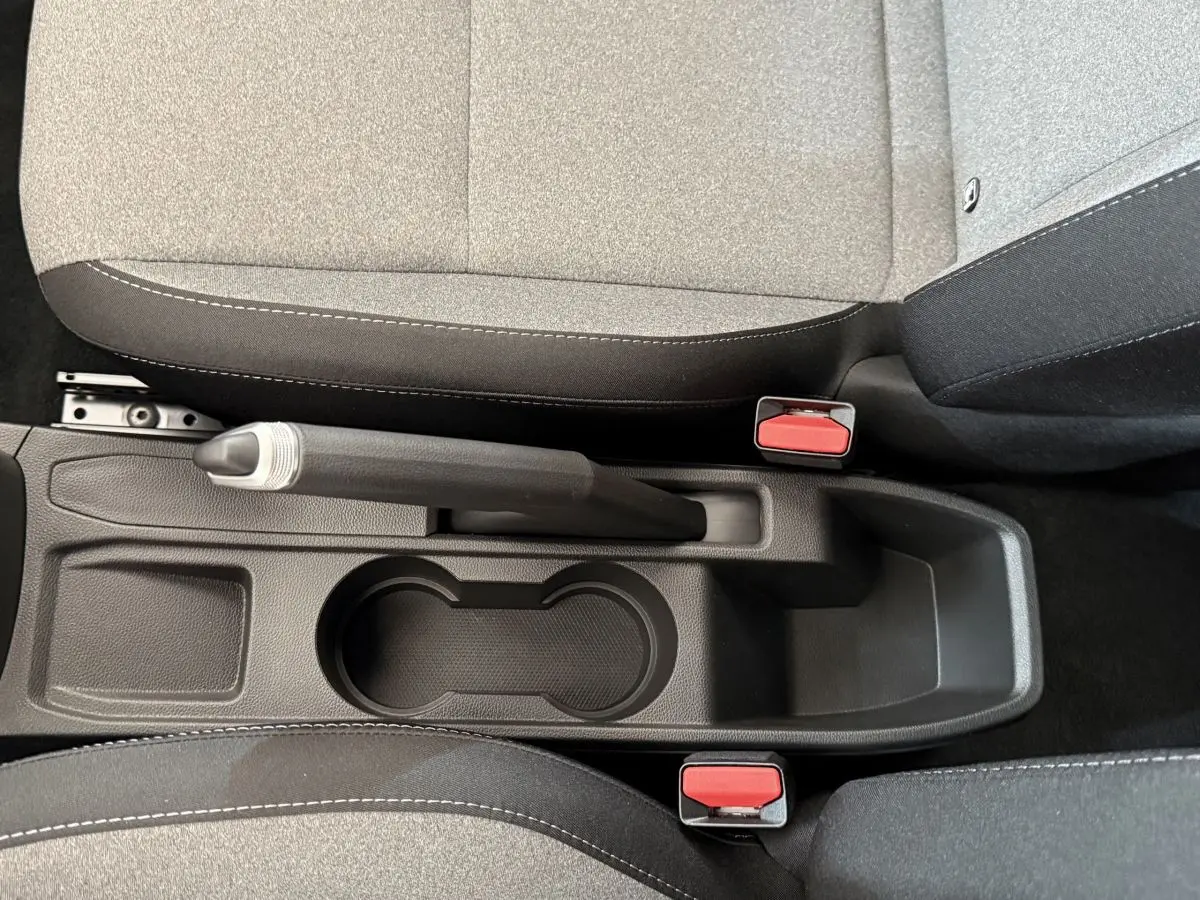 Vue plongeante sur la console centrale noire avec frein à main manuel et sièges tissu gris de la Renault Clio 2025.