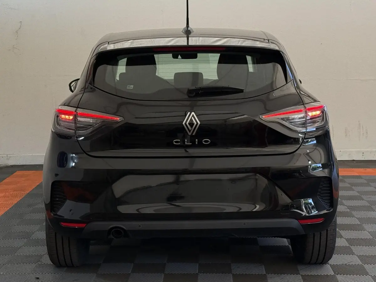 Vue arrière d'une Renault Clio noire 2025 avec feux LED allumés dans un garage intérieur.
