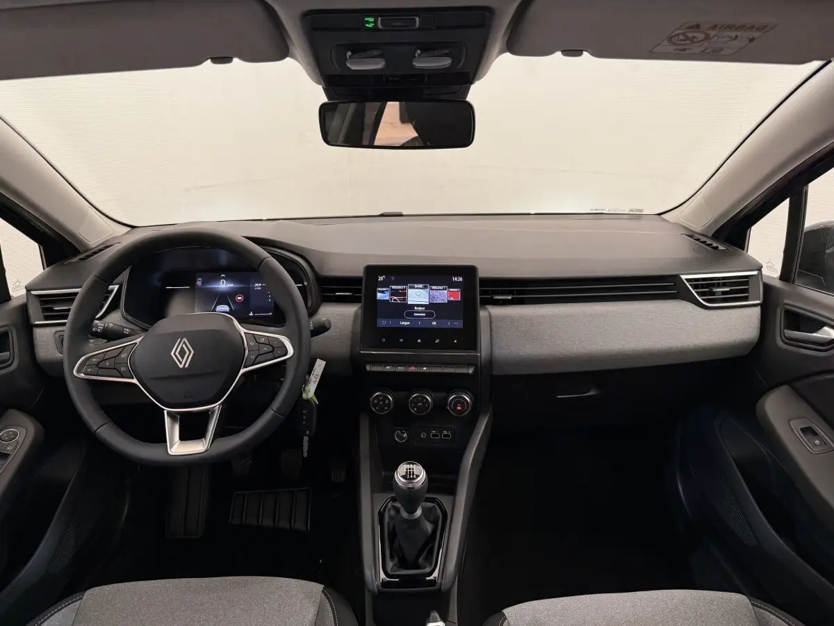 Intérieur de la Renault Clio 2025 en vue frontale, volant cuir noir, écran tactile central et levier de vitesse manuel.
