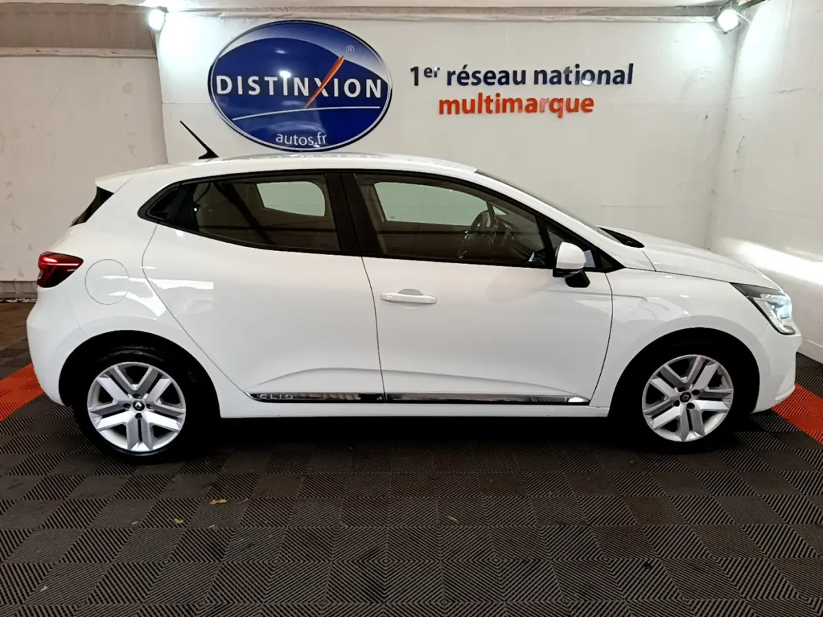 Profil côté gauche d'une Renault Clio Business TCe 100 blanche, avec jantes alliage et poignées de porte assorties.
