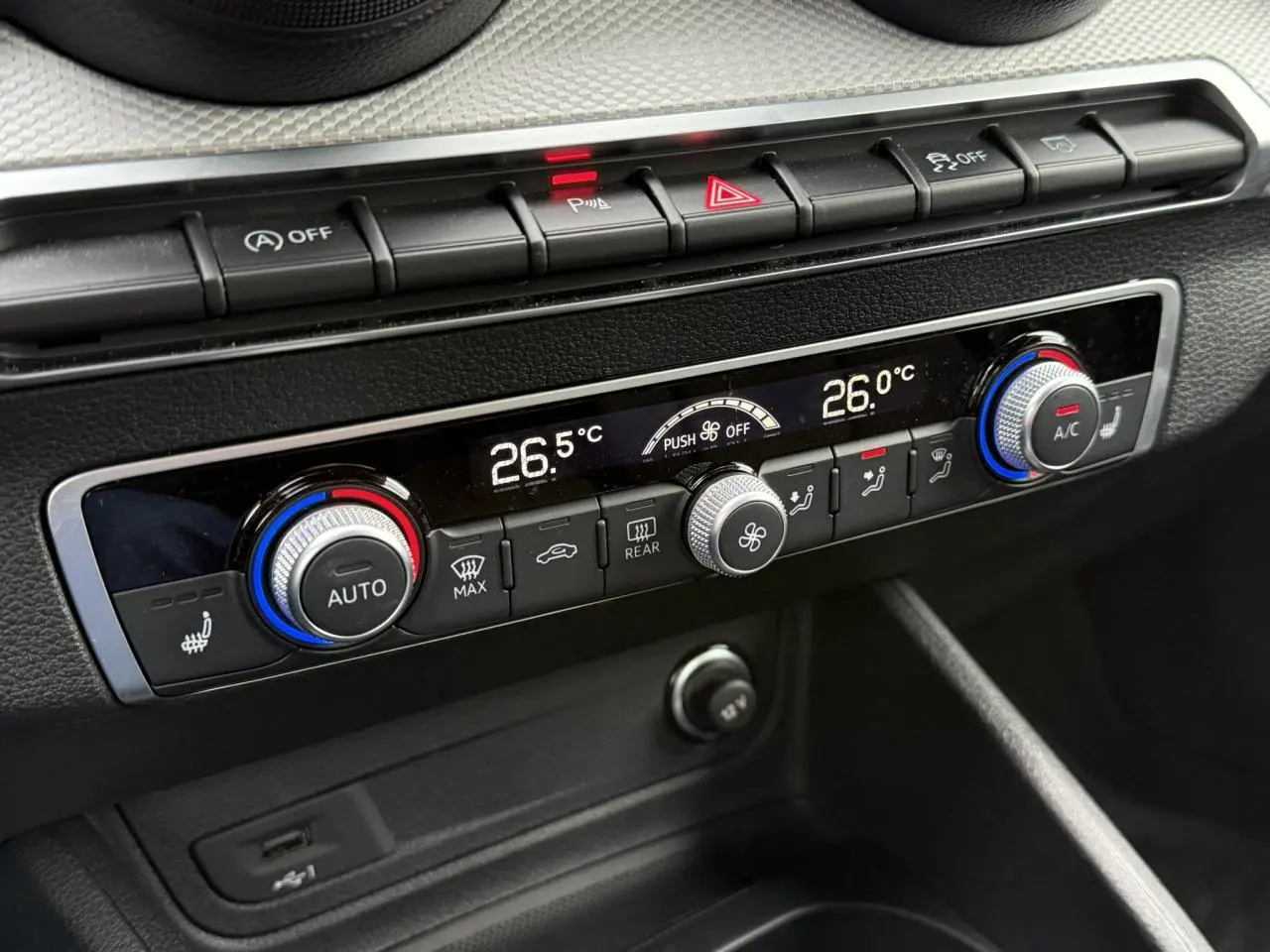 Gros plan sur la console centrale de l'Audi Q2 35 TFSI S-Line 2023, affichant la climatisation automatique à 26°C.