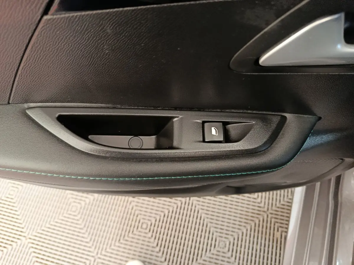 Poignée intérieure de porte côté conducteur de Peugeot 208 2020 avec bouton de verrouillage et surpiqûres bleues.