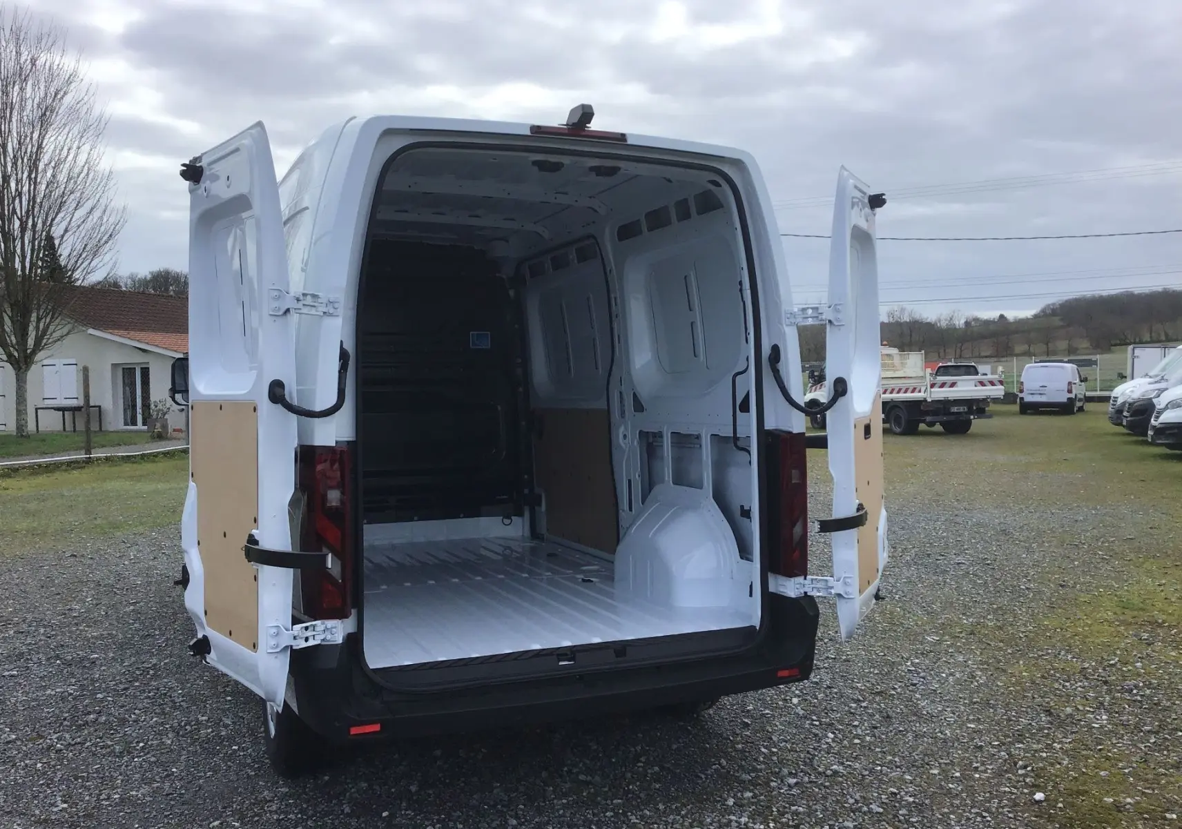 Vue arrière d'un Renault Master blanc avec portes arrière ouvertes, montrant l'espace de chargement vide.