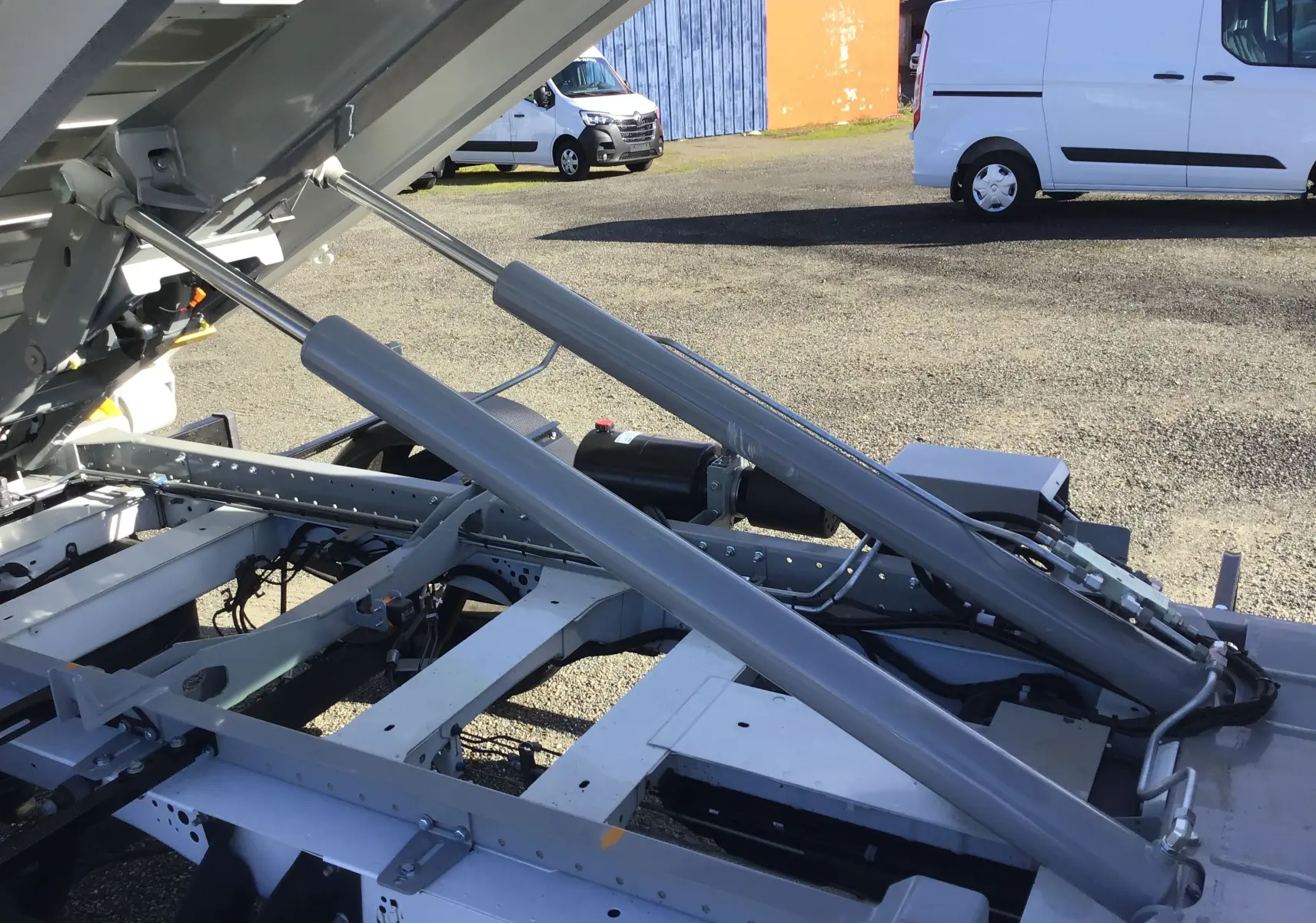 Vue rapprochée du mécanisme de levage hydraulique gris sur le châssis blanc du Ford Transit Chassis Cabine.