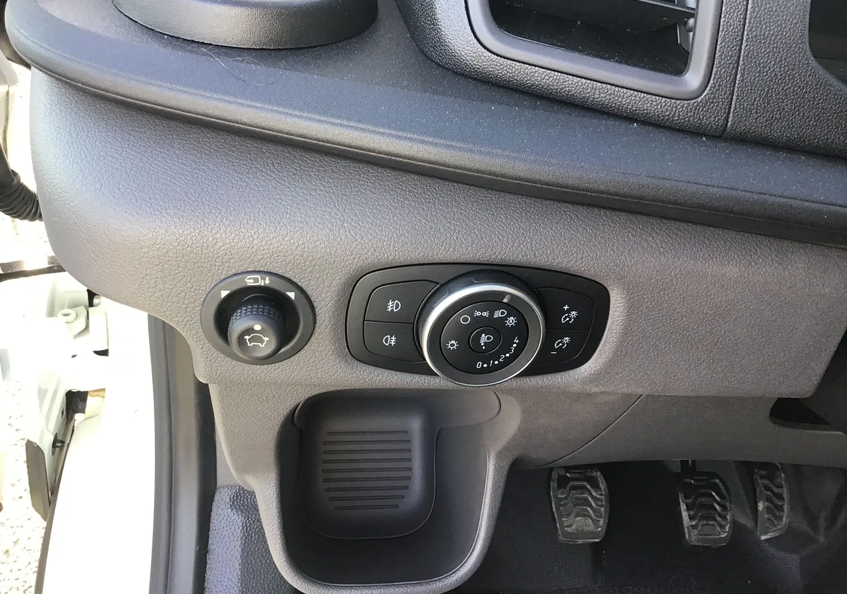 Vue rapprochée du tableau de bord côté gauche du Ford Transit Chassis Cabine blanc, avec commandes d'éclairage et pédales visibles.
