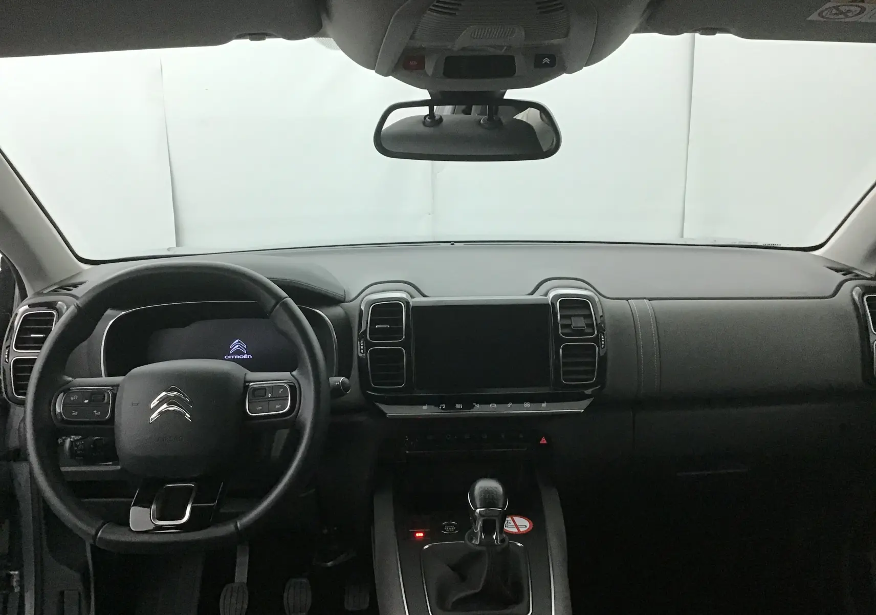 Vue frontale de l'habitacle noir du Citroën C5 Aircross gris, avec tableau de bord moderne et écran tactile central éteint.