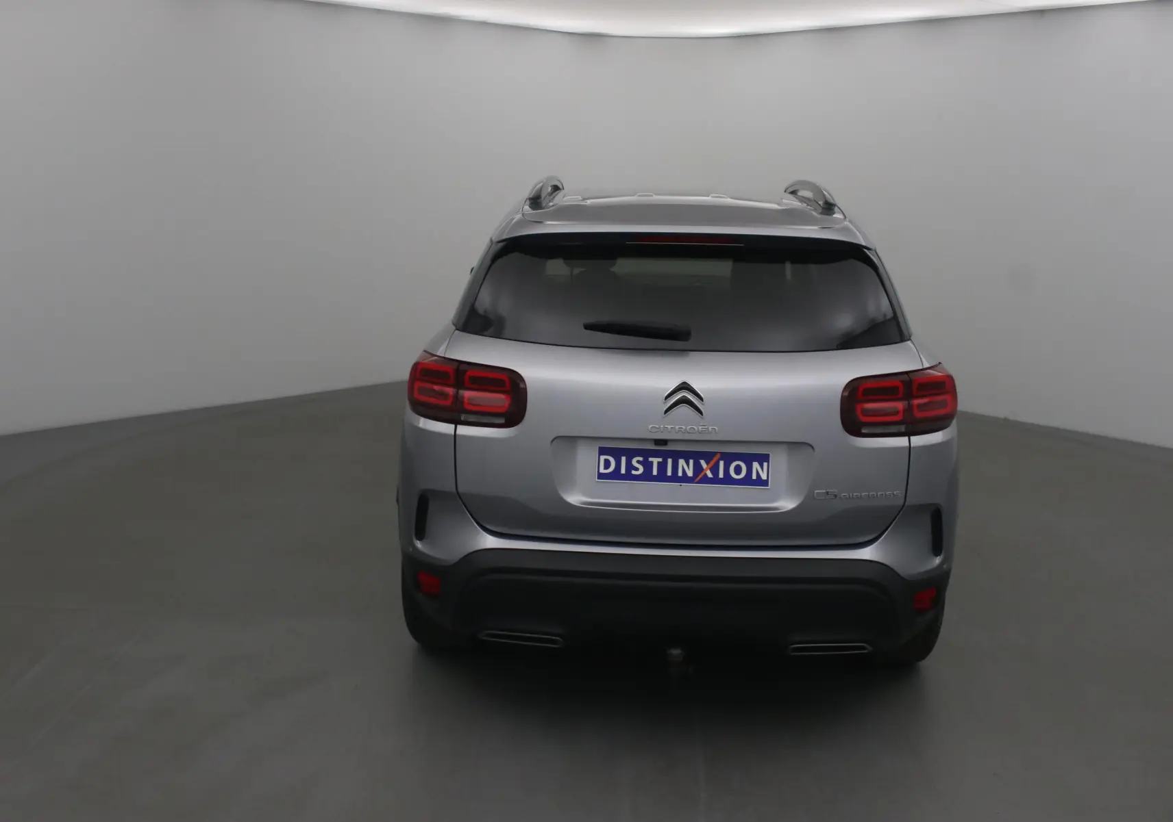 Vue arrière d'un Citroën C5 Aircross gris Artense avec feux arrière LED et attelage visible dans un studio.
