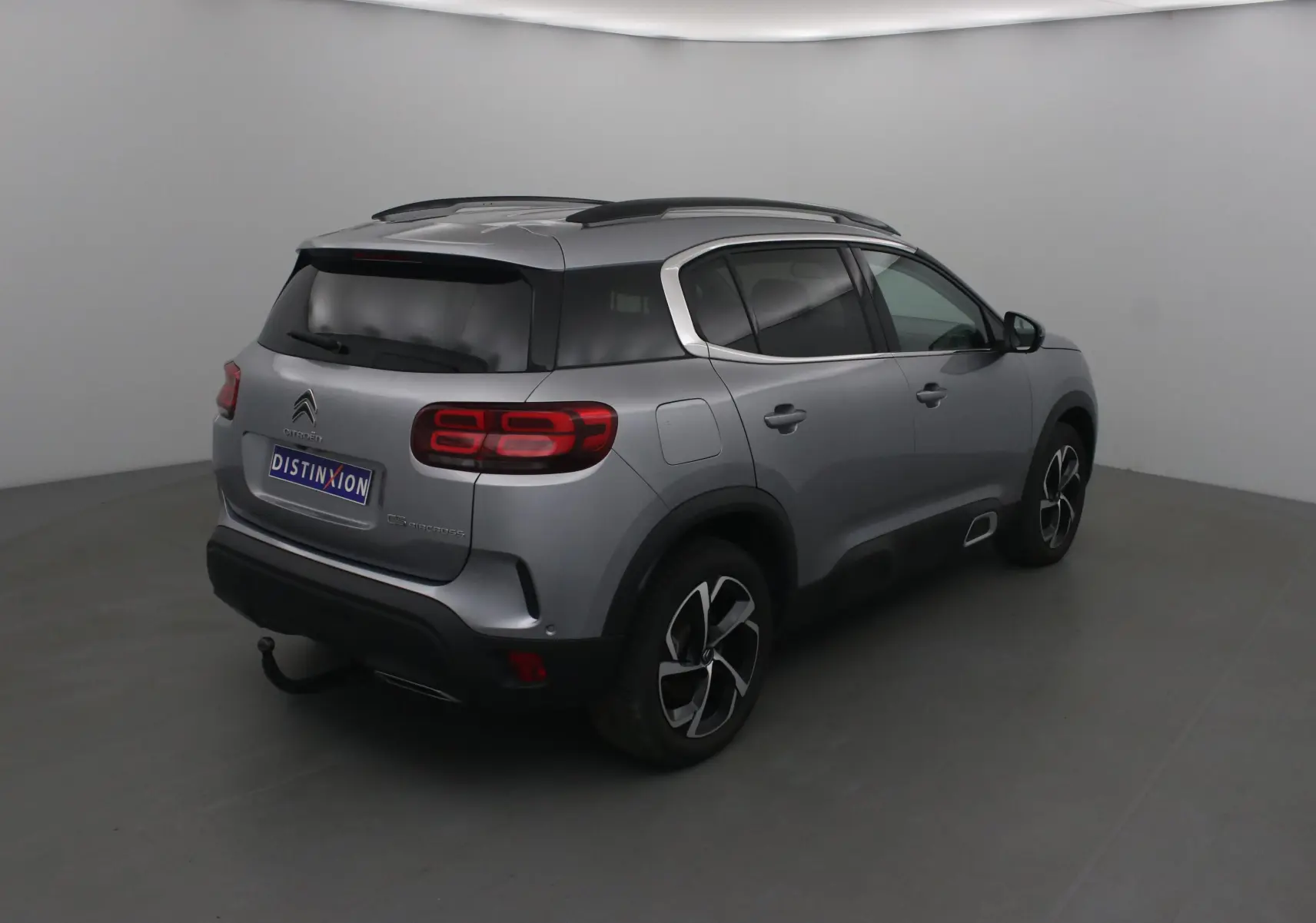 Citroën C5 Aircross gris Artense vu en 3/4 arrière droit, avec jantes noires et toit noir contrasté.