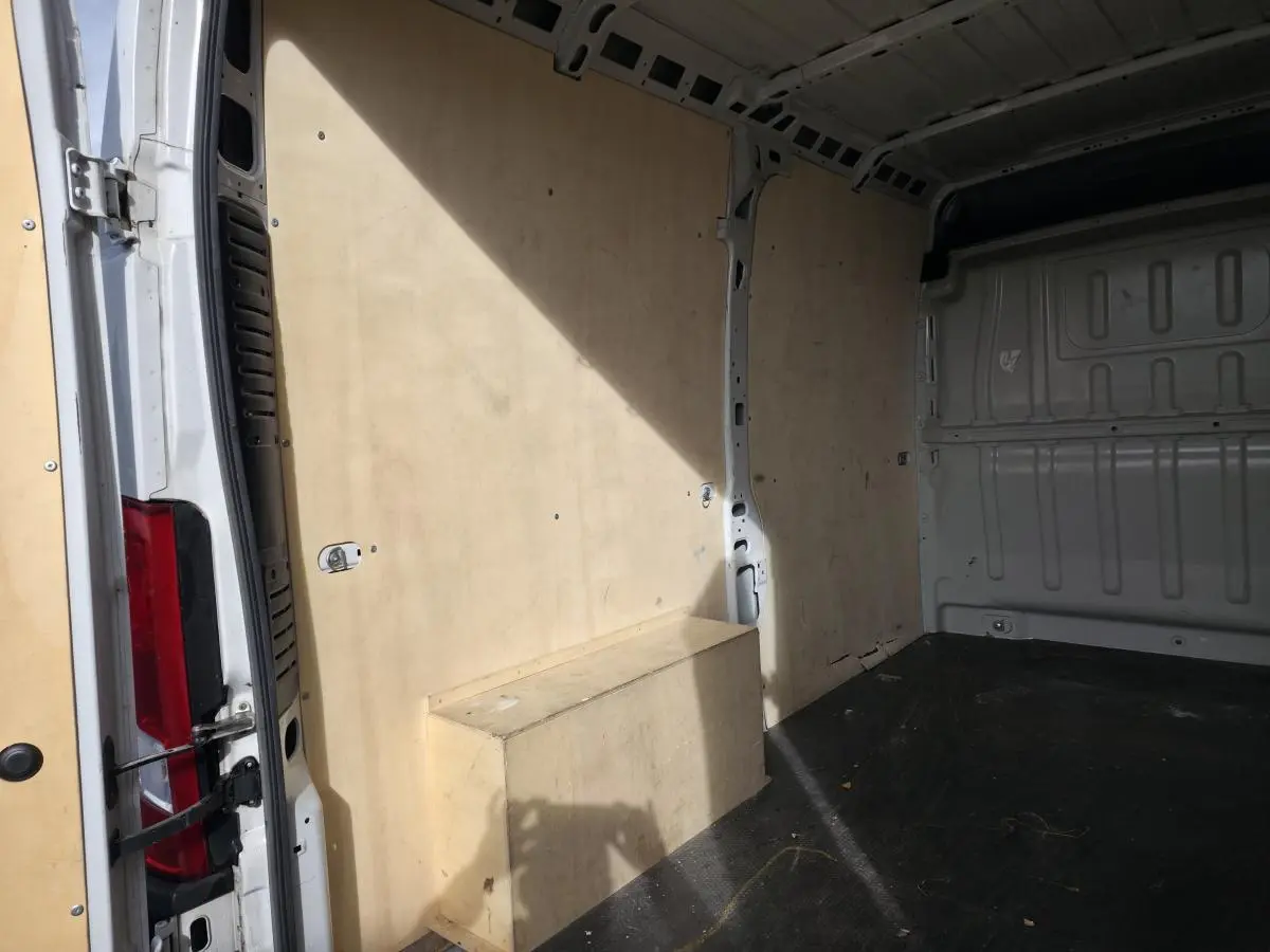 Intérieur du fourgon blanc Opel Movano, vue latérale gauche montrant les panneaux et plancher bois.