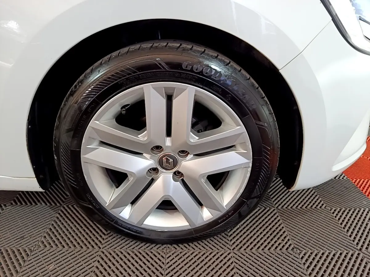 Gros plan sur la roue avant gauche d'une Renault Clio Business blanche, avec jante alliage et pneu Goodyear visible.