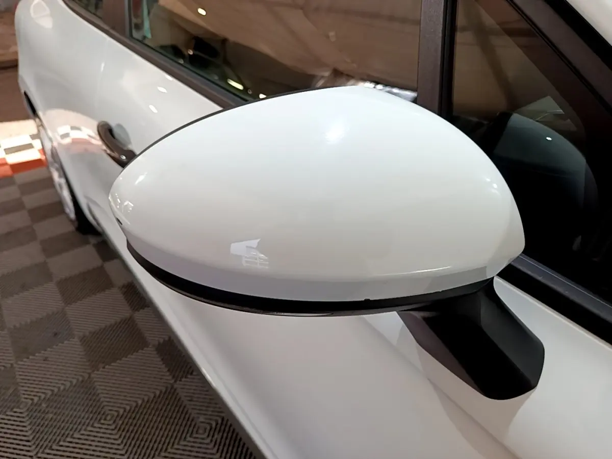 Rétroviseur blanc côté conducteur d'une Renault Clio Business 2021, avec carrosserie blanche visible en arrière-plan.