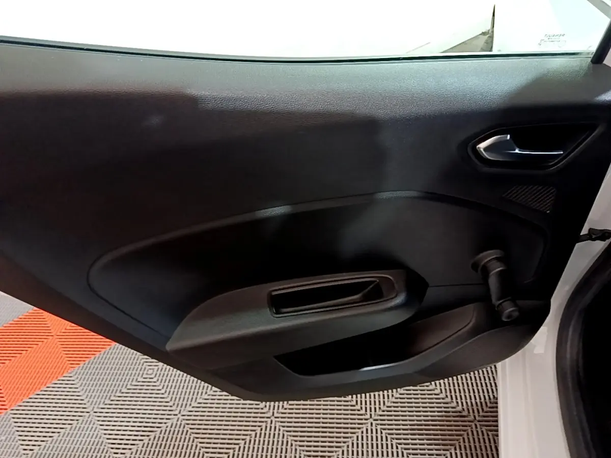 Vue intérieure de la porte arrière droite noire d’une Renault Clio Business blanche avec poignée manuelle de vitre.