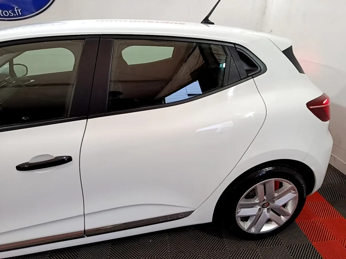 Vue latérale côté gauche d'une Renault Clio blanche avec poignées noires et jantes alliage argentées.