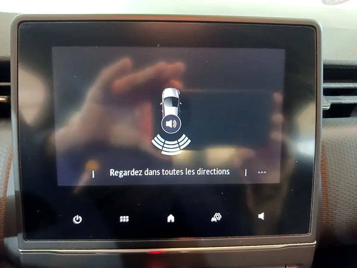 Écran tactile central de la Renault Clio Business blanc, affichant l'alerte de détection d'obstacles arrière.
