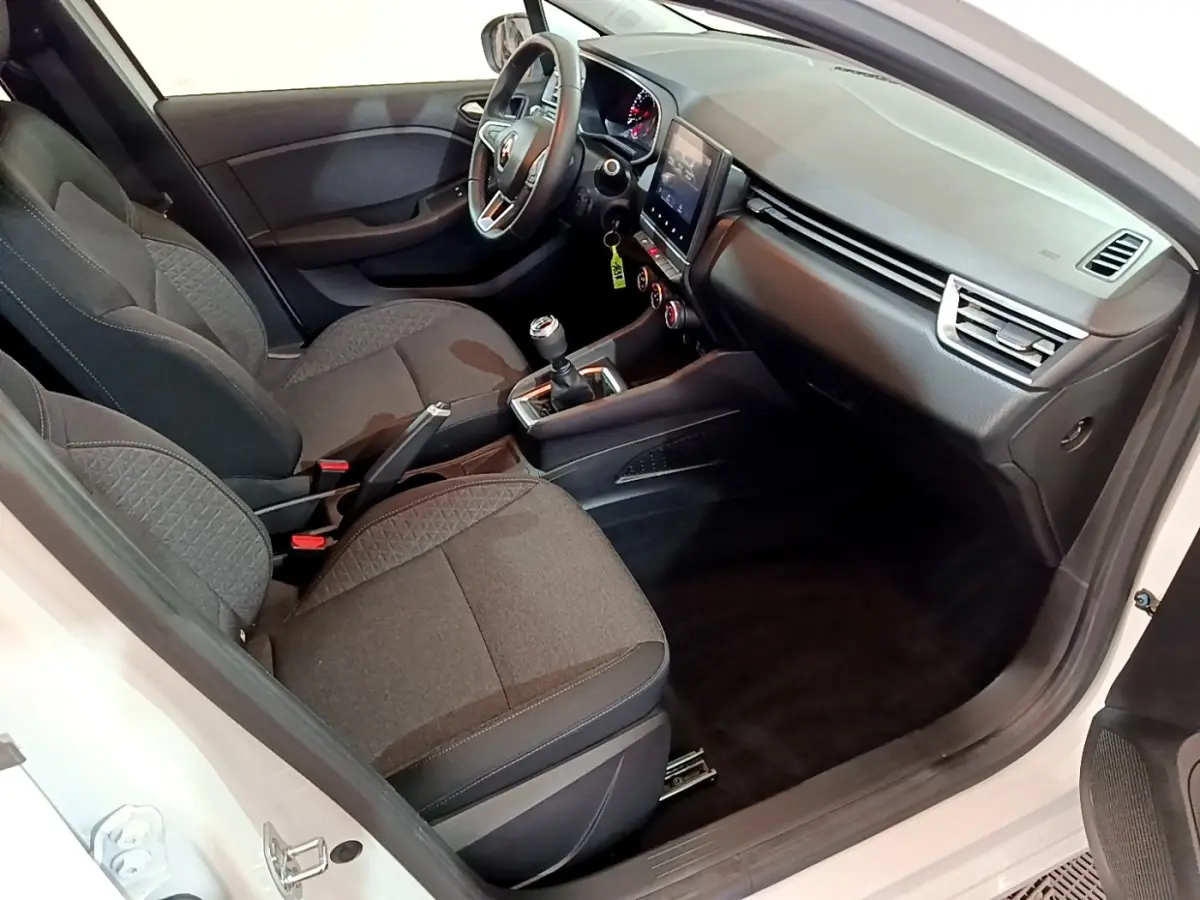 Intérieur vue côté conducteur d’une Renault Clio Business blanche, sièges tissu gris, tableau de bord avec écran tactile vertical.