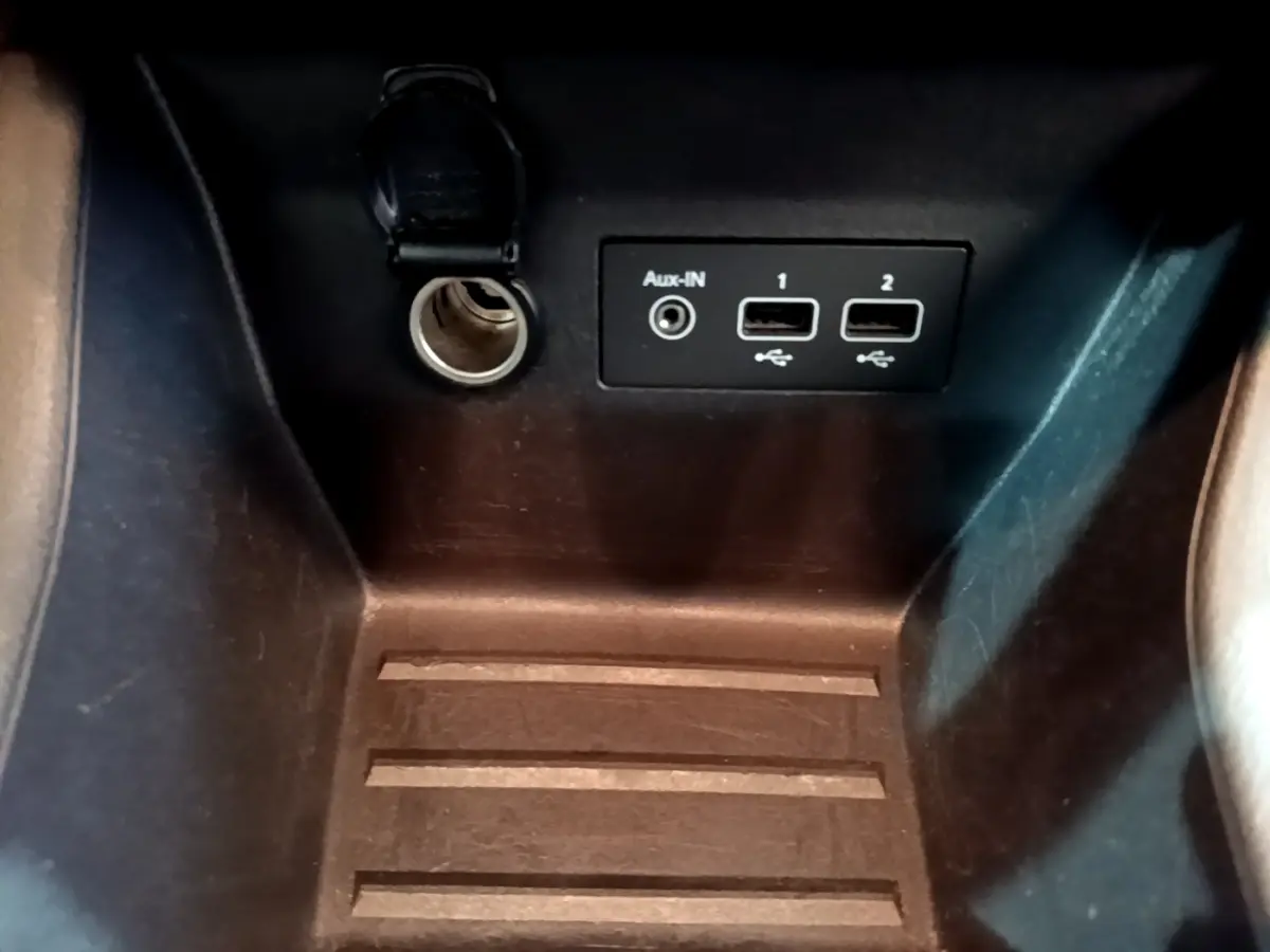 Gros plan sur la prise 12V, port Aux-IN et deux ports USB dans l’espace de rangement intérieur d’une Renault Clio blanche.