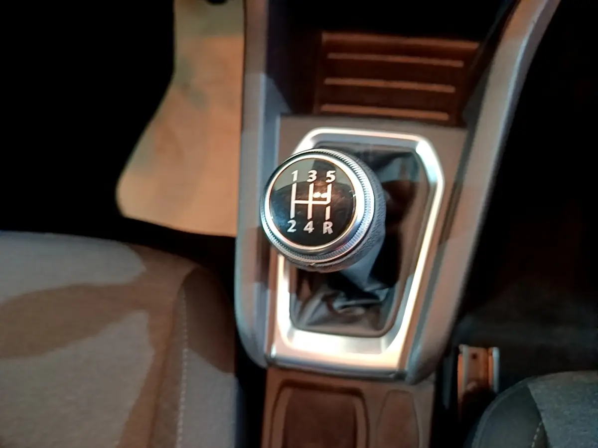 Gros plan sur le levier de vitesse manuel noir et argenté de la Renault Clio Business blanche, intérieur sombre.