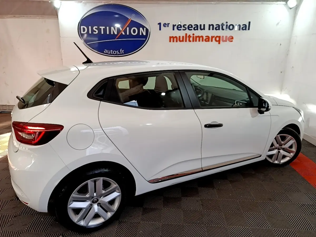 Renault Clio Business blanc vue côté droit en intérieur, avec jantes alliage et feux arrière LED allumés.