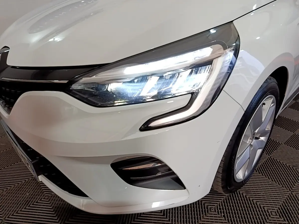 Gros plan sur l'avant droit blanc d'une Renault Clio Business 2021 avec phare LED allumé et jante visible.