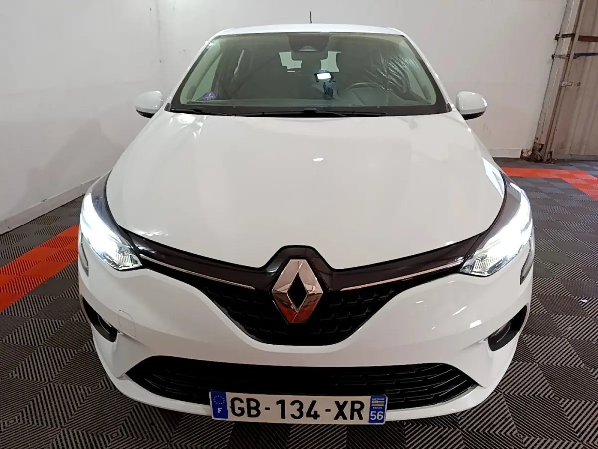 Vue de face d'une Renault Clio Business blanche avec phares LED allumés dans un garage.