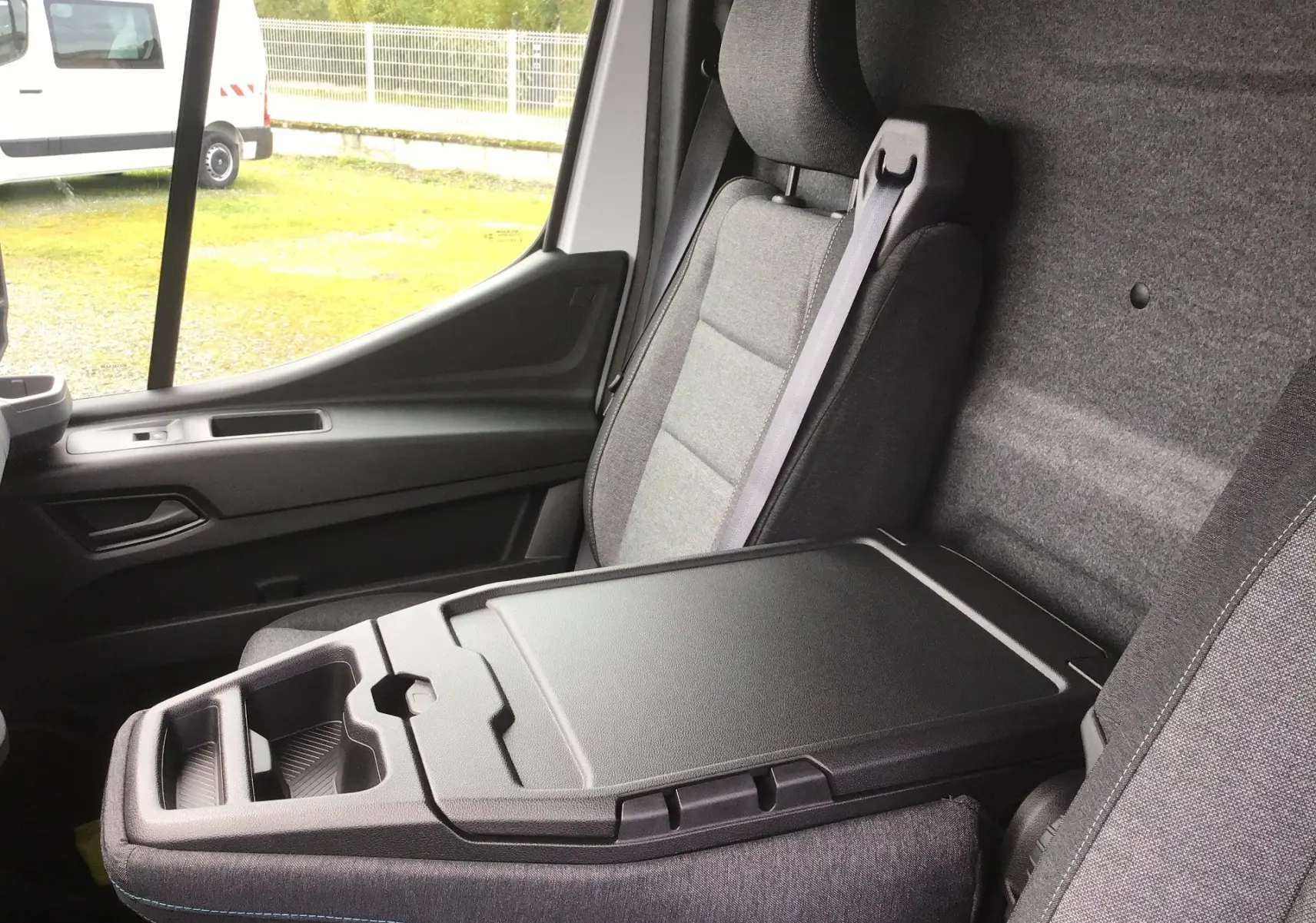 Vue intérieure côté passager du Renault Master blanc 2026, mettant en valeur la banquette bureau mobile et les sièges gris.