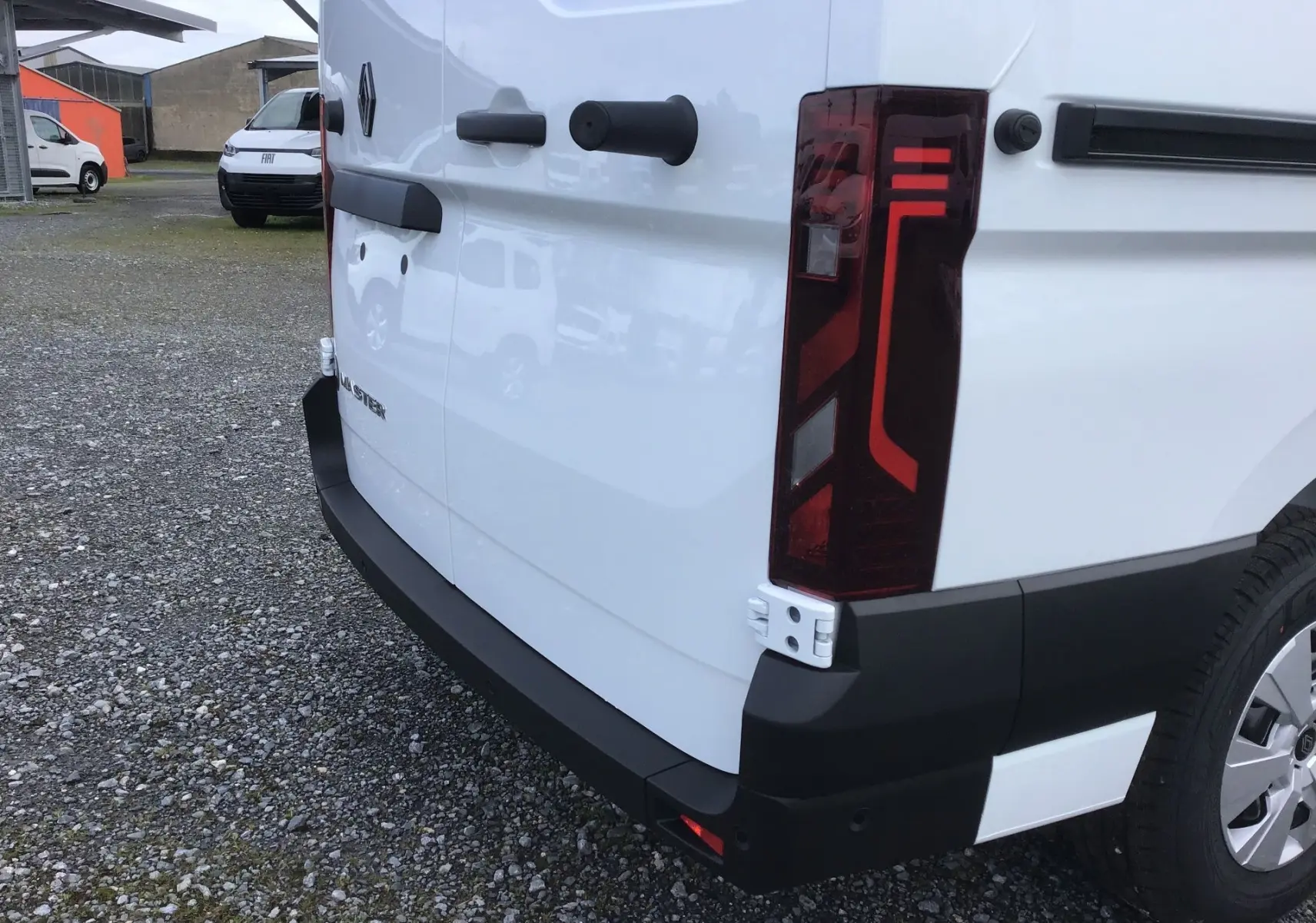 Vue arrière droite d’un Renault Master blanc, mettant en valeur le feu arrière vertical et le pare-chocs noir robuste.