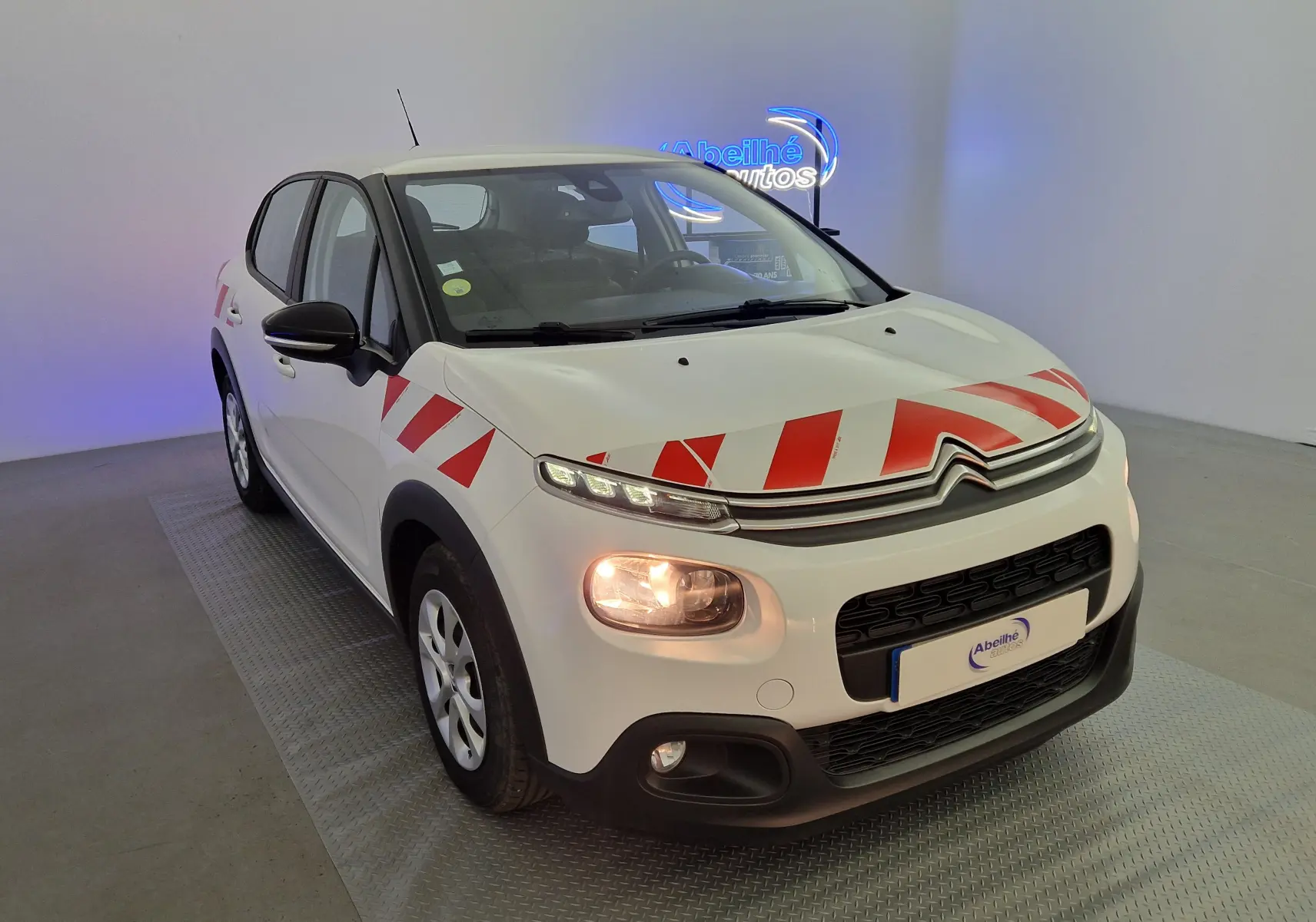 Citroën C3 Société blanche vue 3/4 avant droit avec bandes rouges diagonales sur capot et aile avant.