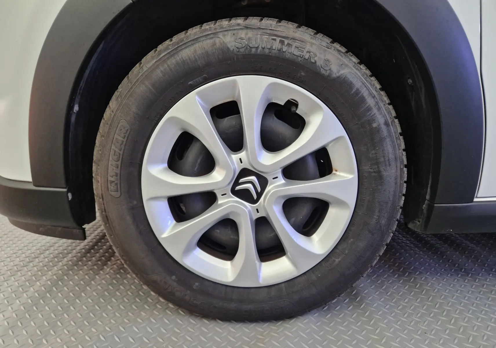 Gros plan sur la roue avant gauche blanche d'une Citroën C3 Société 2019 avec enjoliveur et logo Citroën visible.