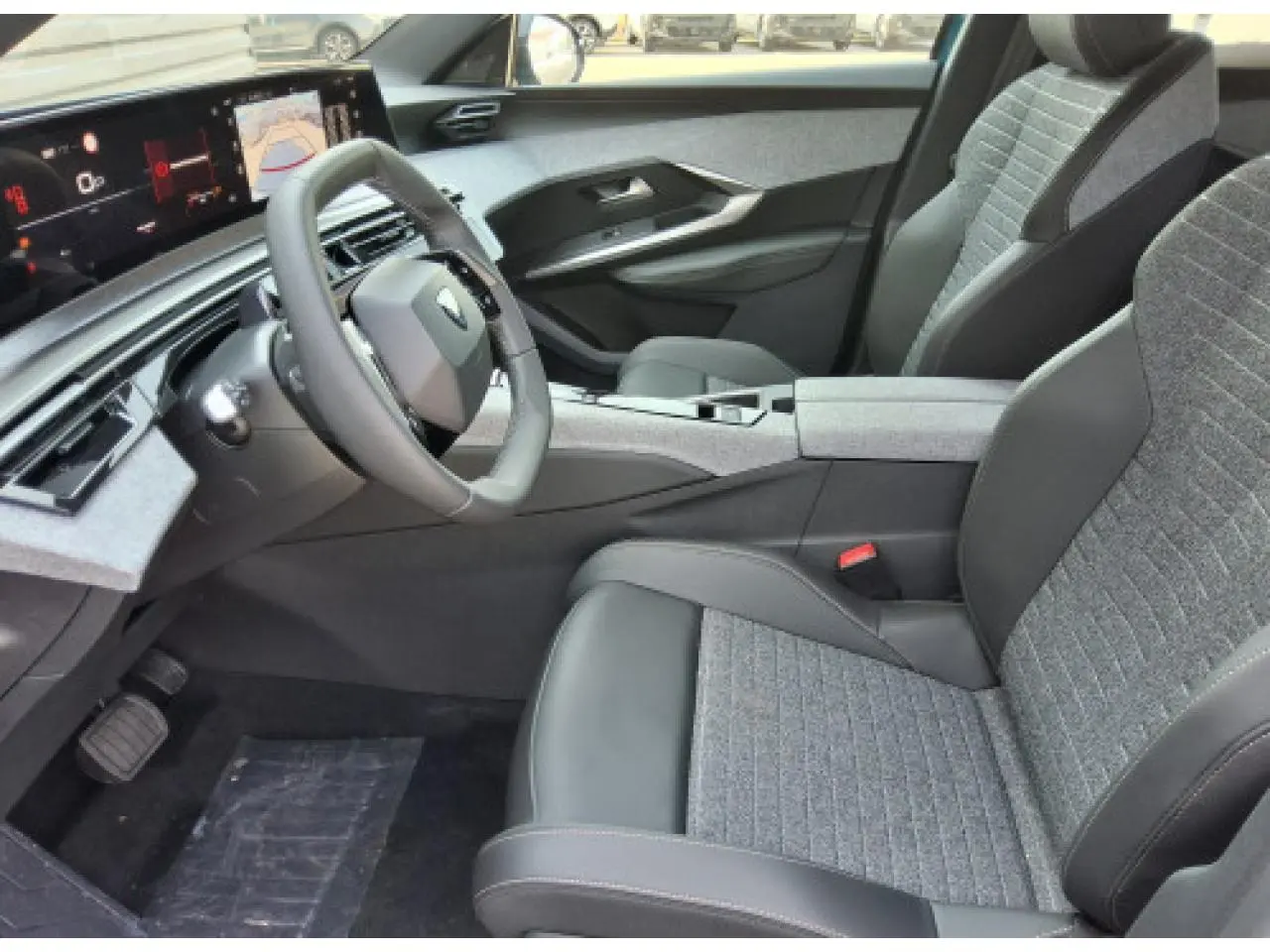 Vue intérieure côté conducteur du Peugeot 3008 Hybrid 2026, avec sièges gris et tableau de bord numérique panoramique.