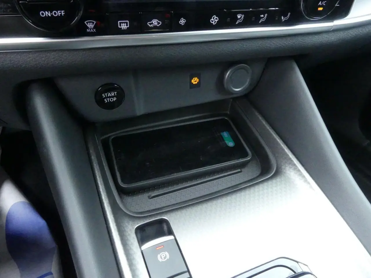 Détail de la console centrale du Nissan Qashqai 2025 avec chargeur à induction et bouton Start/Stop visible.